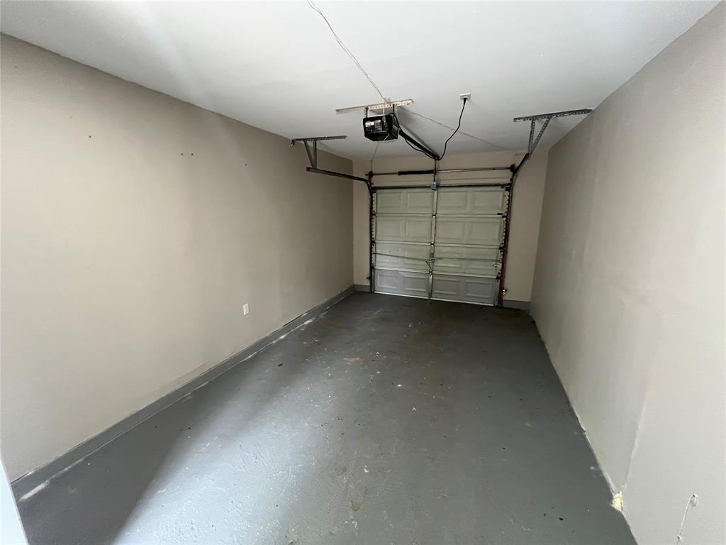 2706 Gross Road Dallas, TX 75228 - Photo 21 of 23 The property features a garage with a roll-up door, painted walls, and a finished floor