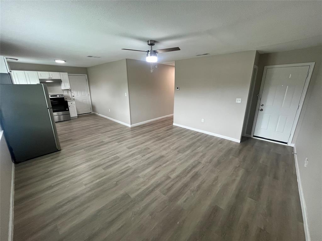 2706 Gross Road Dallas, TX 75228 - Photo 4 of 23 Open concept living area featuring light gray walls, a ceiling fan with integrated lighting, and wood-look flooring