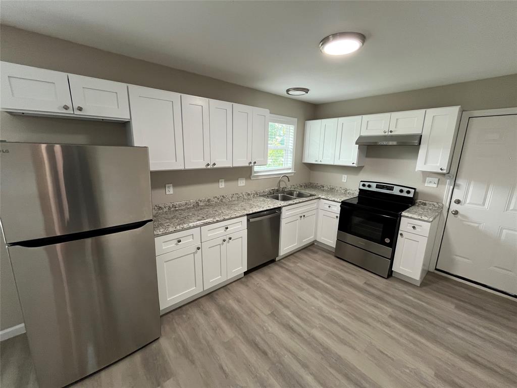 2706 Gross Road Dallas, TX 75228 - Photo 6 of 23 The kitchen features white shaker style cabinetry, granite countertops, stainless steel appliances, and wood-look flooring