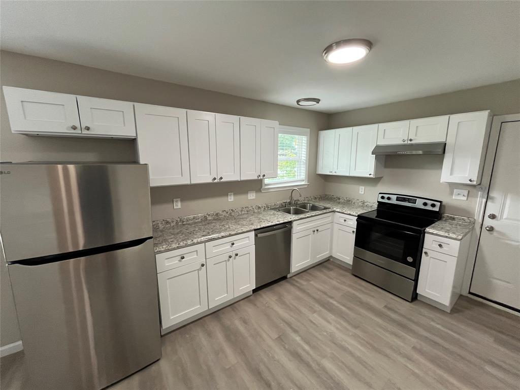 2706 Gross Road Dallas, TX 75228 - Photo 7 of 23 The kitchen features white shaker-style cabinetry, stainless steel appliances, granite-look countertops, and light wood-look flooring