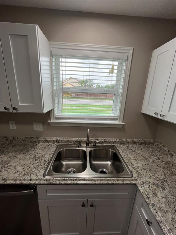 2706 Gross Road Dallas, TX 75228 - Photo 8 of 23 Kitchen featuring a double basin stainless steel sink, a window with blinds, granite countertops, and white cabinetry