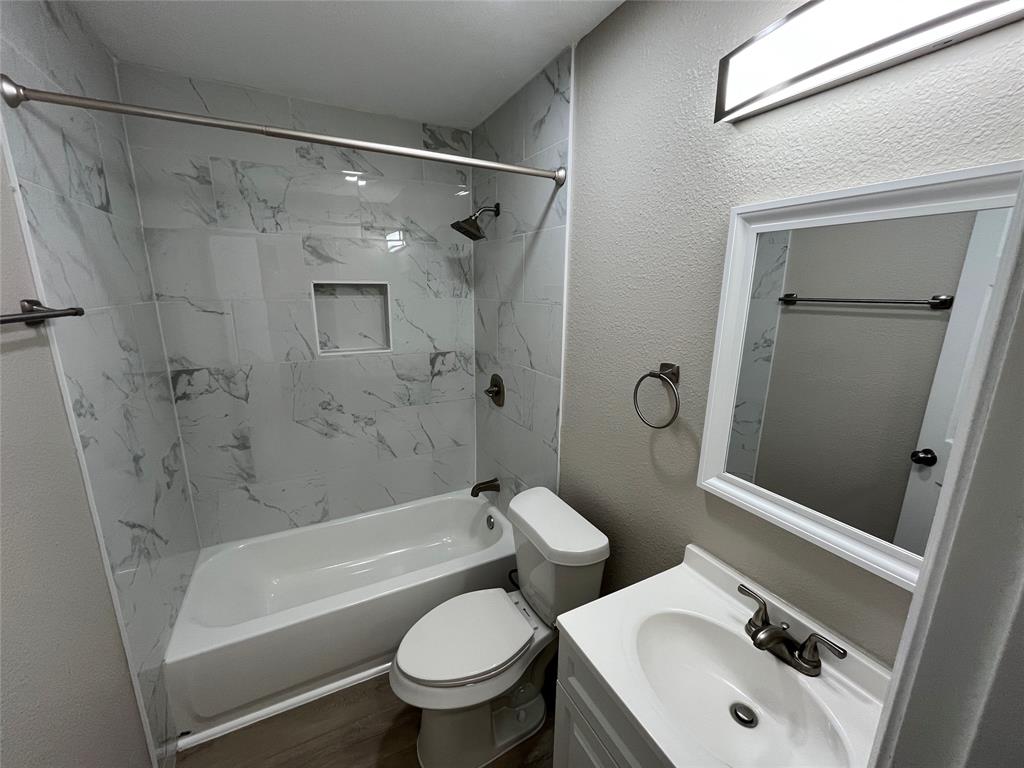 2706 Gross Road Dallas, TX 75228 - Photo 10 of 23 Bathroom featuring a white vanity with a sink, a mirror with a white frame, and a bathtub with white and grey tiled walls