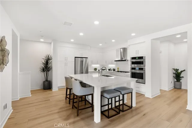 a kitchen with stainless steel appliances kitchen island granite countertop a refrigerator a stove a microwave oven a dining table and chairs with wooden floor