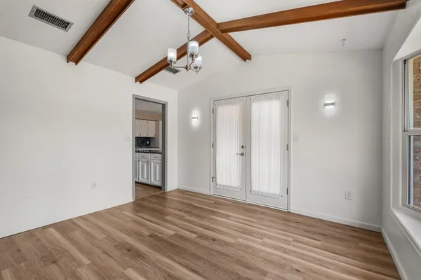 a view of an empty room with wooden floor and a window