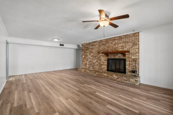 a view of an empty room with wooden floor and a fireplace