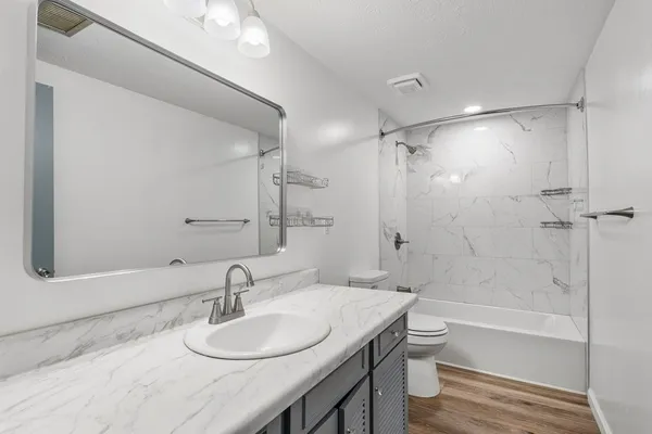 a bathroom with a granite countertop sink toilet and shower