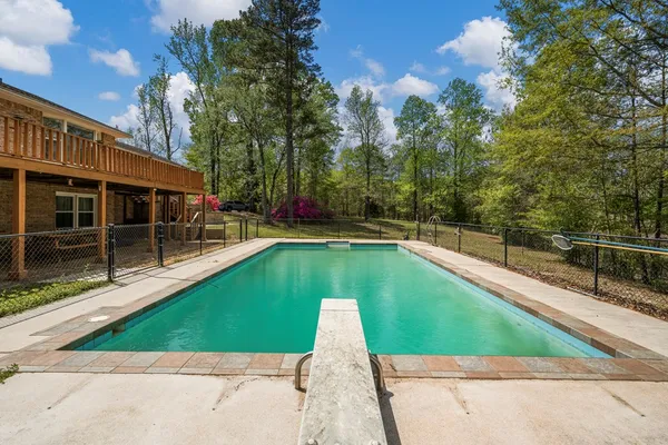 a view of a swimming pool with a patio and a yard