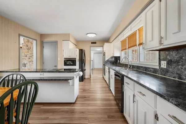 a kitchen with stainless steel appliances granite countertop a stove a sink and a microwave