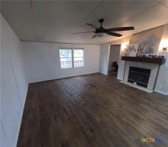a view of an empty room with wooden floor and a fireplace
