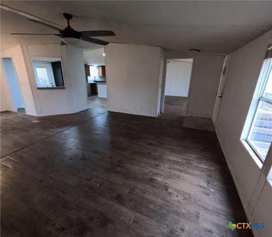an empty room with wooden floor and a ceiling fan