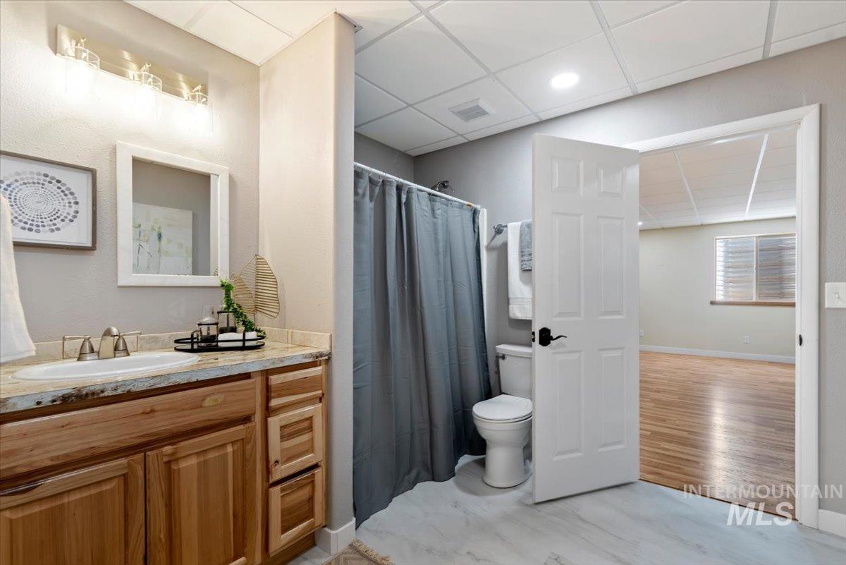 147 East Indian Crk Road Boise, ID 83716 - Photo 27 of 43 Bathroom featuring a wood-finish vanity with an undermount sink, a light-toned countertop, and a shower with a gray curtain