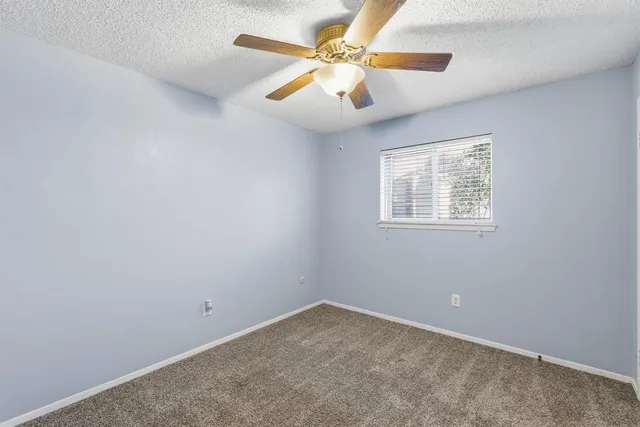 an empty room with a window and a fan