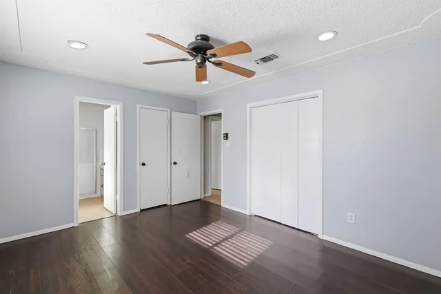 a view of an empty room with wooden floor and a ceiling fan