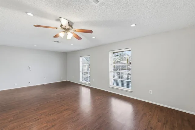 a view of an empty room with window and wooden floor