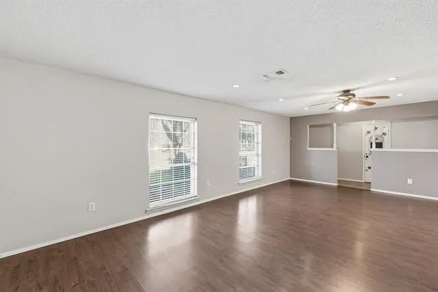 a view of an empty room with a window and wooden floor