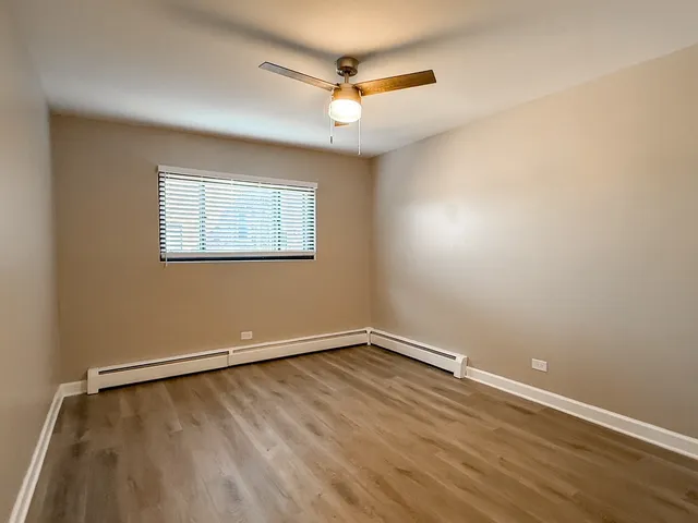 an empty room with a window and a ceiling fan
