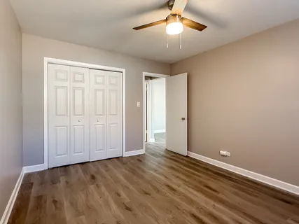 an empty room with wooden floor chandelier fan and closet area