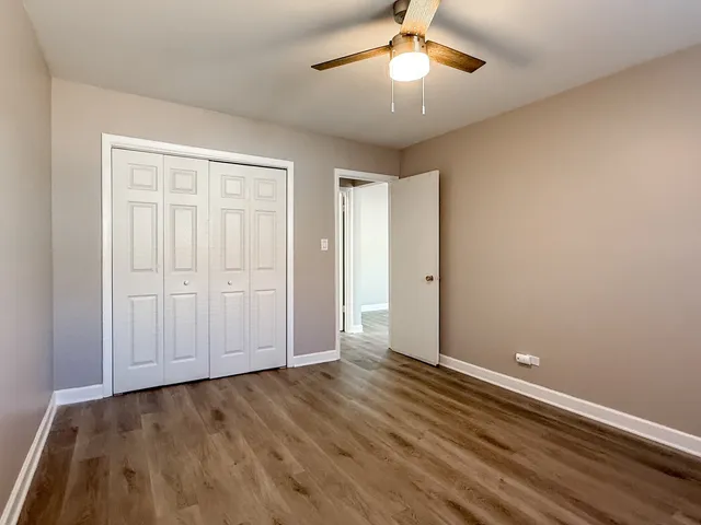an empty room with wooden floor chandelier fan and closet area