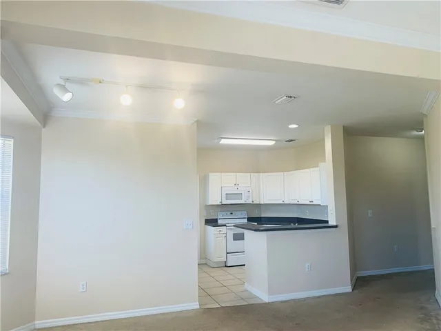 a view of kitchen with granite countertop white cabinets and stainless steel appliances