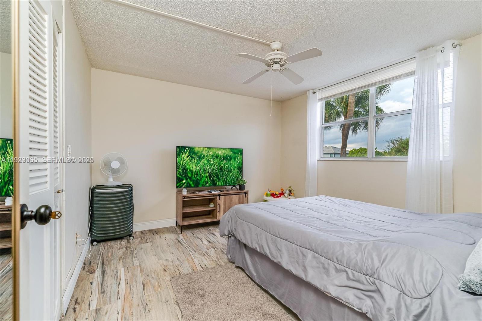 2840 Somerset Drive, Unit 207M Lauderdale Lakes, FL 33311 - Photo 17 of 25 a bedroom with a large bed and a chandelier