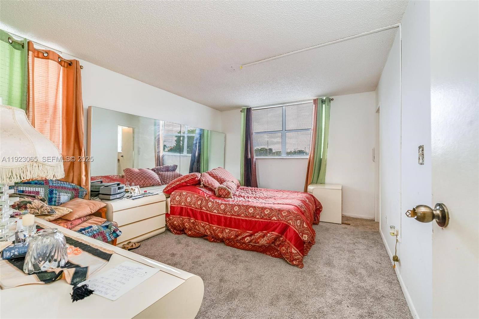 2840 Somerset Drive, Unit 207M Lauderdale Lakes, FL 33311 - Photo 18 of 25 a bedroom with bed and a large mirror next to a window