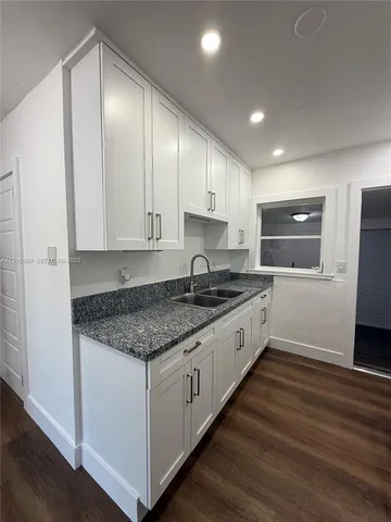 a large kitchen with granite countertop a sink and cabinets