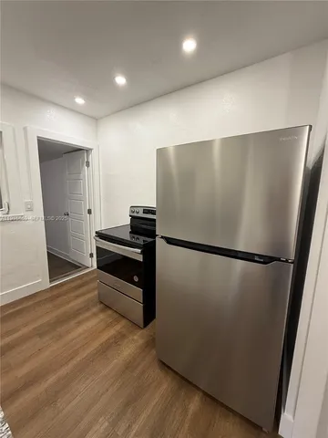a view of a kitchen with refrigerator and wooden floor