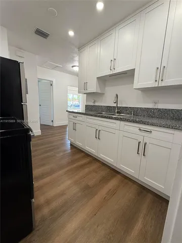 a kitchen with granite countertop white cabinets and black stainless steel appliances