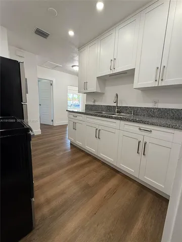 a kitchen with granite countertop white cabinets and black stainless steel appliances