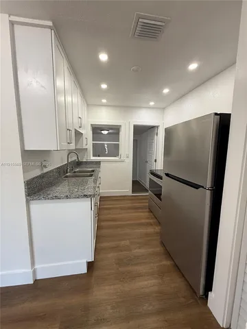 a kitchen with stainless steel appliances granite countertop a refrigerator a sink a stove and a wooden floors