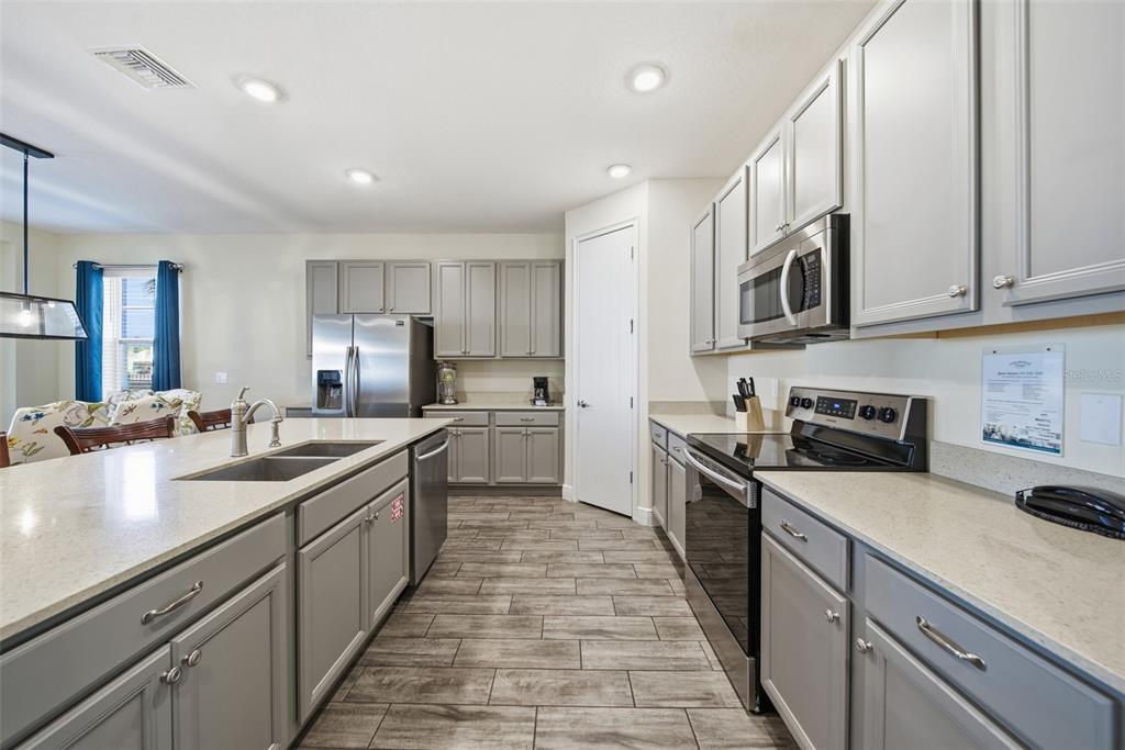 8017 Surf Street Kissimmee, FL 34747 - Photo 17 of 64 a large kitchen with stainless steel appliances granite countertop a sink and dishwasher a stove top oven with wooden floor