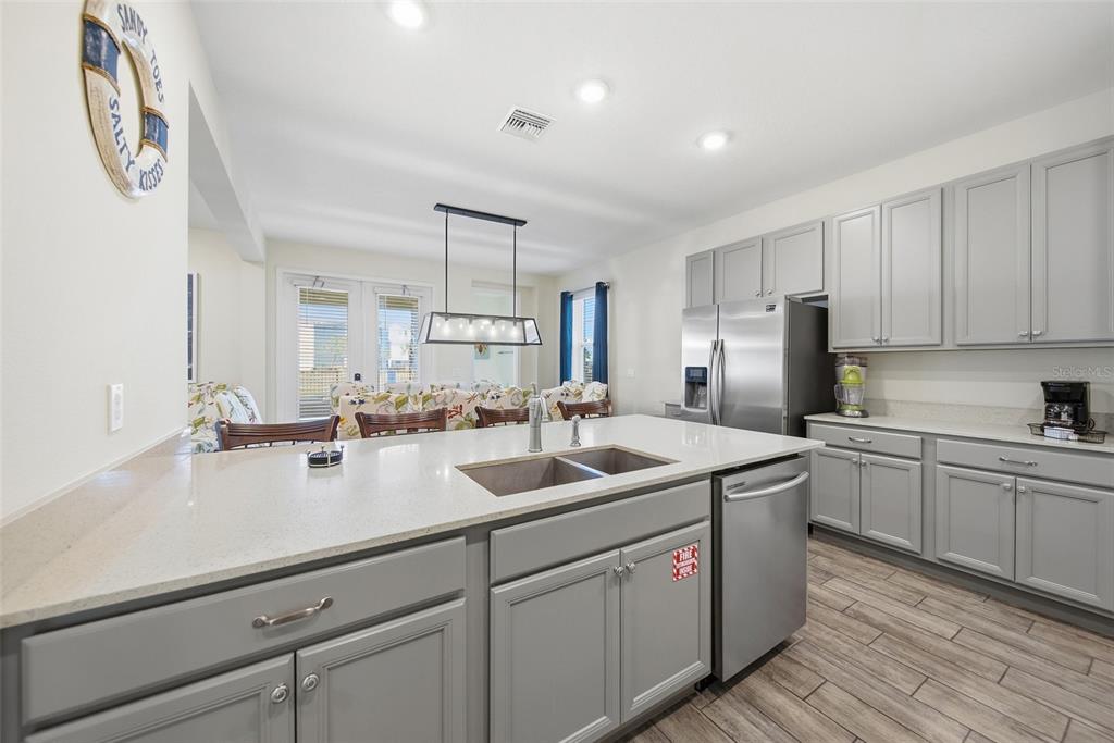 8017 Surf Street Kissimmee, FL 34747 - Photo 19 of 64 a kitchen with a sink dishwasher a stove and a refrigerator with wooden floor