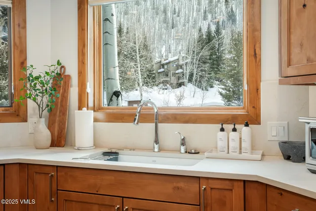a kitchen with a sink and a large mirror next to a window