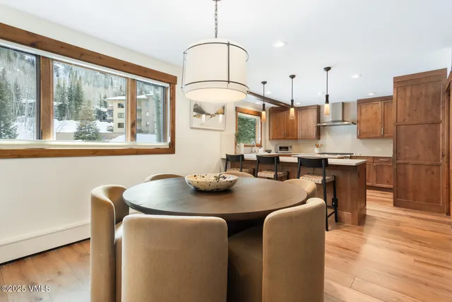 a kitchen with stainless steel appliances granite countertop a table chairs stove and wooden floor