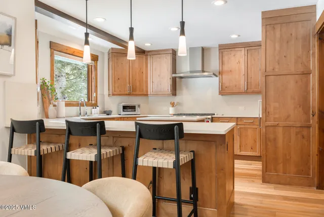 a kitchen with stainless steel appliances a refrigerator a sink a stove a dining table and chairs