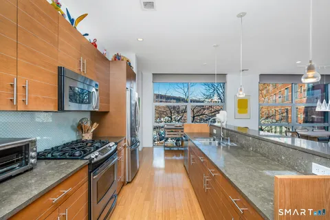 a kitchen with stainless steel appliances granite countertop a stove and a wooden floors