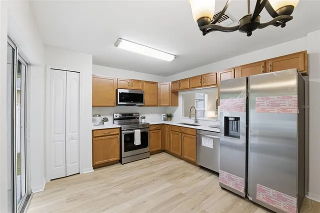 a kitchen with stainless steel appliances granite countertop a refrigerator a stove top oven a sink and dishwasher with wooden floor