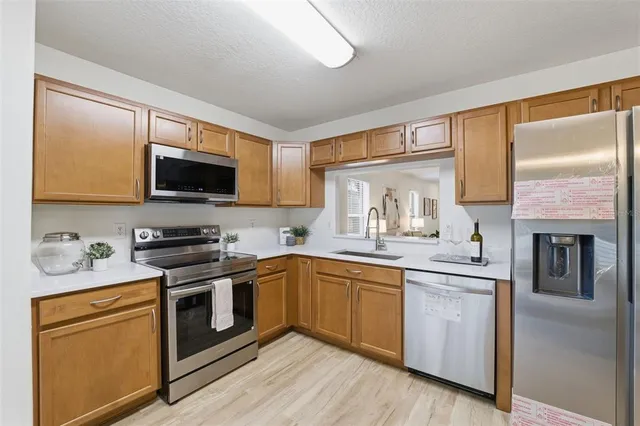 a kitchen with stainless steel appliances granite countertop a stove top oven a sink dishwasher a microwave oven and a refrigerator with wooden floor