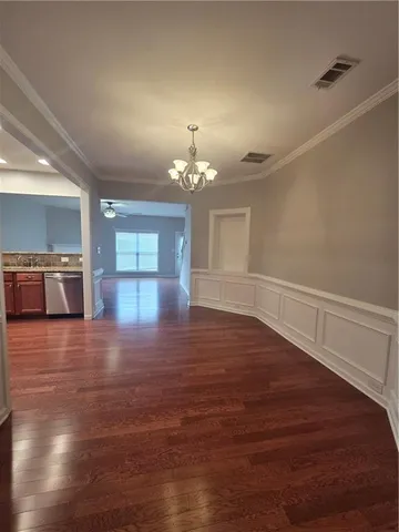 a view of empty room with wooden floor and kitchen