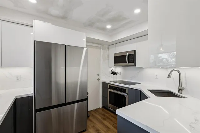 a kitchen with stainless steel appliances wooden floor sink and refrigerator