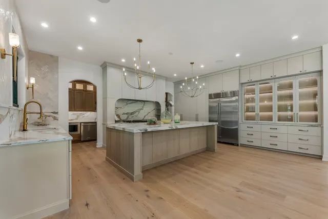 a large kitchen with stainless steel appliances kitchen island a large counter top a sink a stove and a window