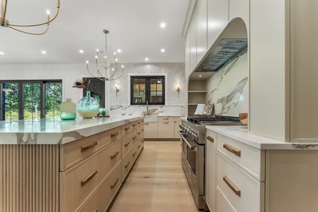 a large kitchen with stainless steel appliances kitchen island a large counter tops and a chandelier