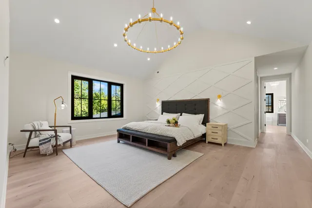 a spacious bedroom with a bed a mirror and a large window