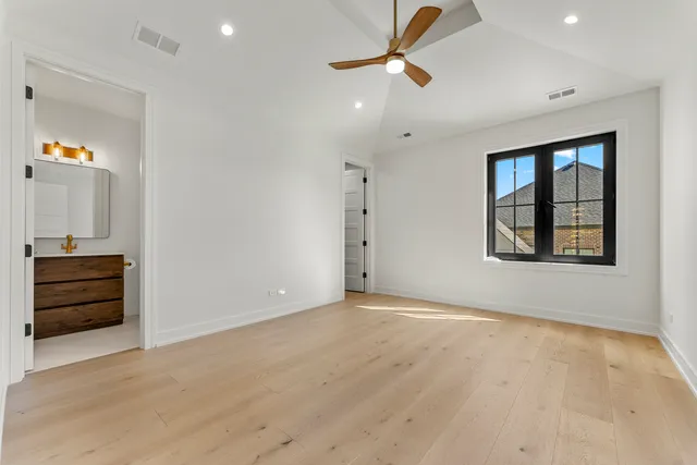 an empty room with wooden floor cabinet and windows
