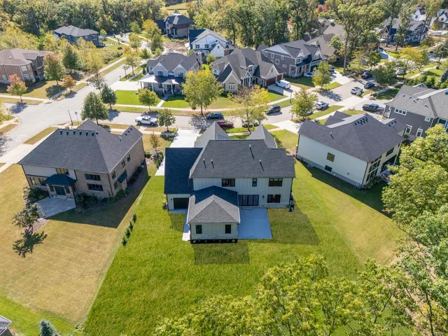 an aerial view of a house with swimming pool and large trees