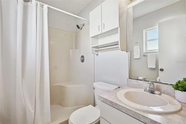 a bathroom with a granite countertop sink toilet a mirror and shower