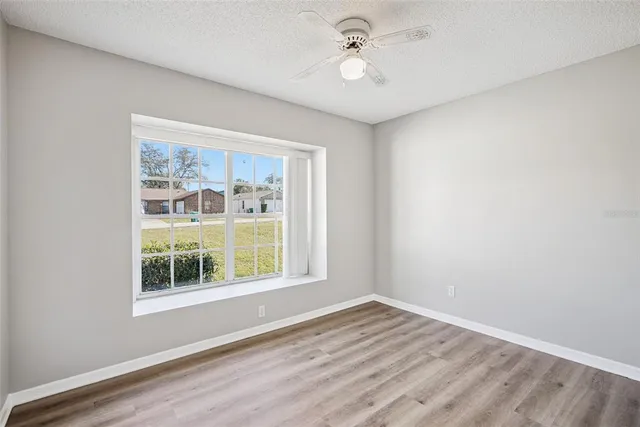 a view of empty room with wooden floor and fan