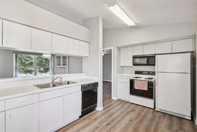 a kitchen with a sink white cabinets stainless steel appliances and window