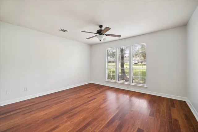 an empty room with wooden floor and windows