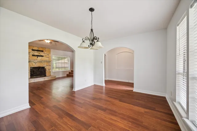 a view of a room with wooden floor fireplace and windows